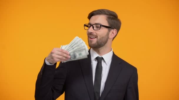 Уверенный бизнесмен показывает долларовые купюры и подмигивания, высокооплачиваемую работу, наличные — стоковое видео