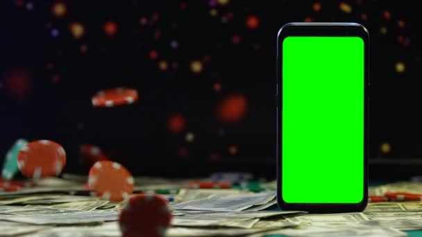 Chips de juego cayendo en dólares en el fondo del teléfono inteligente con pantalla verde — Vídeos de Stock