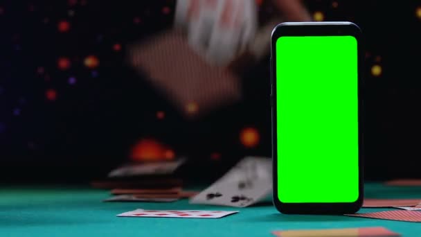Smartphone με πράσινη οθόνη στέκεται πάνω σε υπόβαθρο της πτώσης τραπουλόχαρτα — Αρχείο Βίντεο