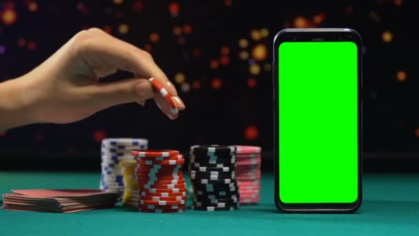 Казино жетоны и карты, лежащие рядом с зеленым экраном смартфона, онлайн азартные игры — стоковое видео