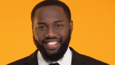 Sarı arka plan üzerinde izole kamera içine gülümseyerek başarılı Afro-Amerikan erkek
