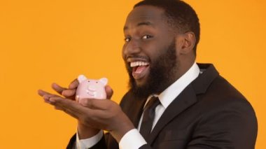 Kumbara sallayarak Afro-Amerikan erkek gülümseyen, mevduat Bankacılığı sunar