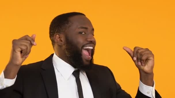 Homme noir en costume se déplaçant vers la musique sur fond jaune, danse de la victoire — Video