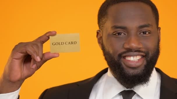 Souriant oligarque afro-américain tenant la carte d'or, avantages de la vie réussie — Video