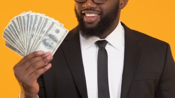 Hombre negro excitado señalando con el dedo a un montón de dólares, servicios de crédito, banca — Vídeo de stock