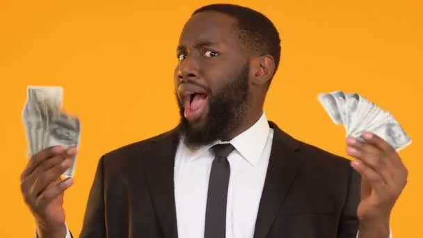 Extremadamente feliz hombre afro-americano agitando montón de dólares, beneficio de puesta en marcha — Vídeos de Stock