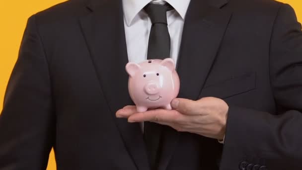 Banker hält Sparschwein mit beiden Händen, Zuverlässigkeit und Investitionssicherheit — Stockvideo