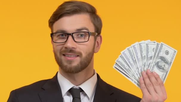 Smiling man holding cash in hand, perks and bonuses, isolated bright background — Stock Video