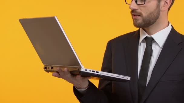 Растерянный мужчина показывает все в порядке и подмигивает, тестируя новое приложение на своем ноутбуке — стоковое видео