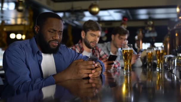 Homens perturbados usando celulares no bar, entediados sozinhos nos fins de semana, vício em gadgets — Vídeo de Stock