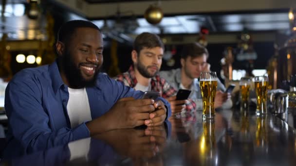 Homens solitários sentados no pub, olhando através de sites de namoro em celulares, vício — Vídeo de Stock