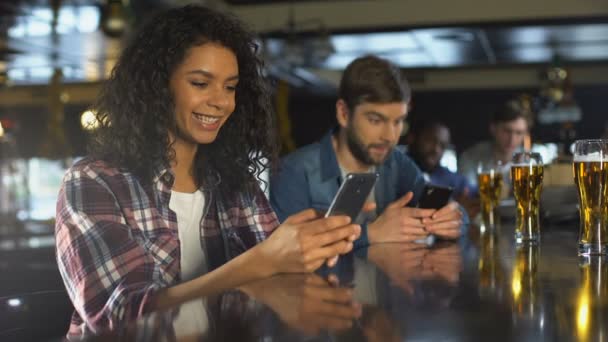 Молодые люди используют телефоны в баре, игнорируя живое общение, концепцию зависимости — стоковое видео