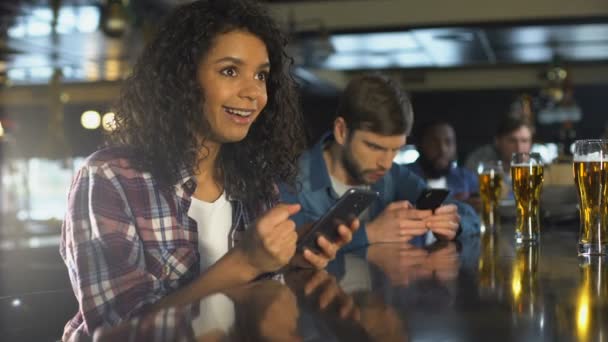 Biracial chica en el bar celebrando la apuesta exitosa en los deportes, aplicación de corredor de apuestas en línea — Vídeo de stock