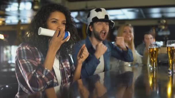 Mannelijke en vrouwelijke voetbal fans ondersteunende voetbalelftal in pub, genieten van de overwinning — Stockvideo
