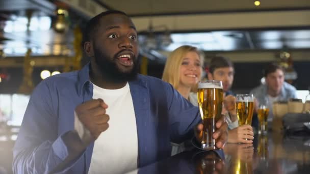 Багаторасові друзі виховують келихи пива, відзначаючи успіх спортивної команди — стокове відео
