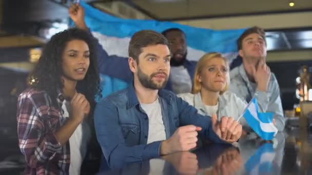 Fãs do esporte com a bandeira da Argentina apoiando a equipe no jogo, preocupando-se em ganhar — Vídeo de Stock