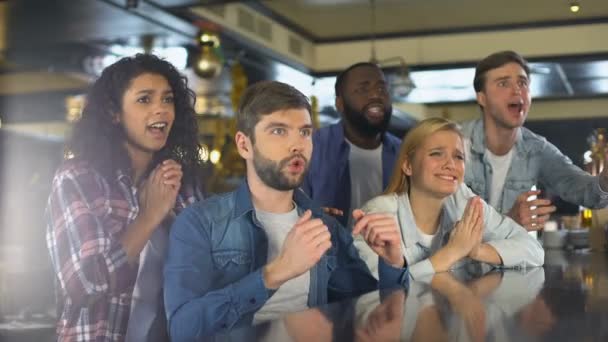Группа друзей смотрит спортивную программу в баре, расстроена проигрышем игры, поражением — стоковое видео