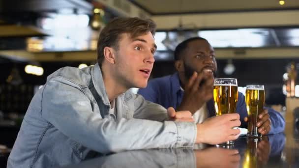 Amigos masculinos excitados batendo copos de cerveja apoiando a equipe nacional, enraizamento — Vídeo de Stock