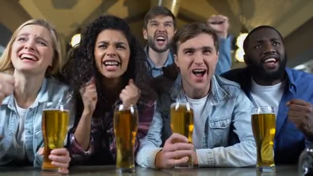 Joyosos partidarios del equipo gritando y tintineando vasos de cerveza, celebrando gol — Vídeo de stock