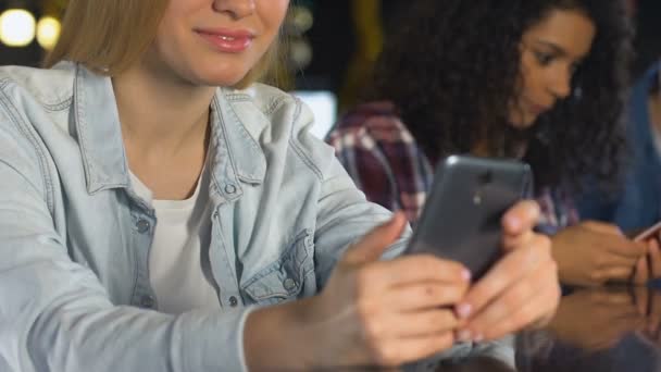 Улыбающиеся женщины болтают на смартфонах в баре, используют приложения для знакомств — стоковое видео