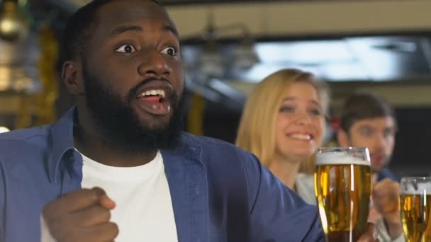 Молодые люди с пивом смотрят скачки в баре, болеют за победу — стоковое видео