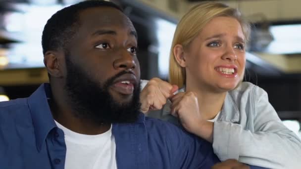 Pareja multirracial emocionalmente viendo el juego deportivo en el bar, animando por la victoria — Vídeos de Stock