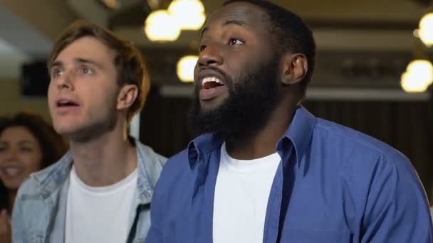 Young men having fun in bar, watching football game, cheering for victory — Wideo stockowe