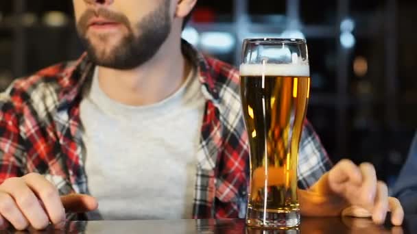 Мужской болельщик смотрит спортивные соревнования, сидит в баре и пьет свежее пиво — стоковое видео