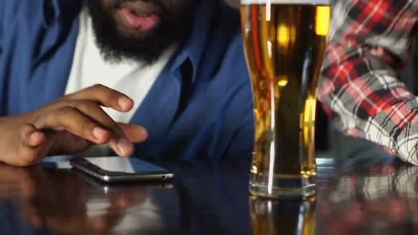 Hombre afroamericano haciendo apuestas en aplicación en su teléfono inteligente, viendo el juego de deportes — Vídeos de Stock