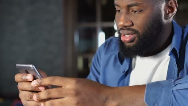 Όμορφος Αφρικανός Αμερικανός άνθρωπος συνομιλεί με την κοπέλα στην εφαρμογή στο smartphone — Αρχείο Βίντεο
