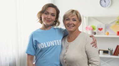 Yaşlı kadın ve kadın gönüllü gösteren thumbs yukarı sarılmak, yardım emekli insanlar