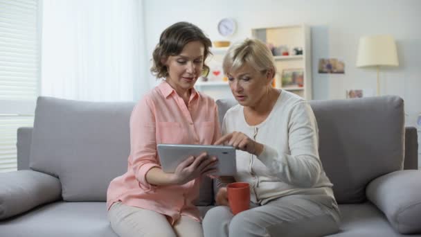 Mulher branca com mãe idosa usando tablet, aplicação de pagamento fácil — Vídeo de Stock