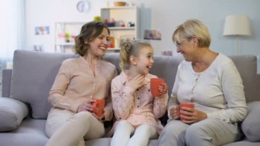 Kadın aile üyeleri birlikte çay bardakları ile ev kanepede otururken konuşan