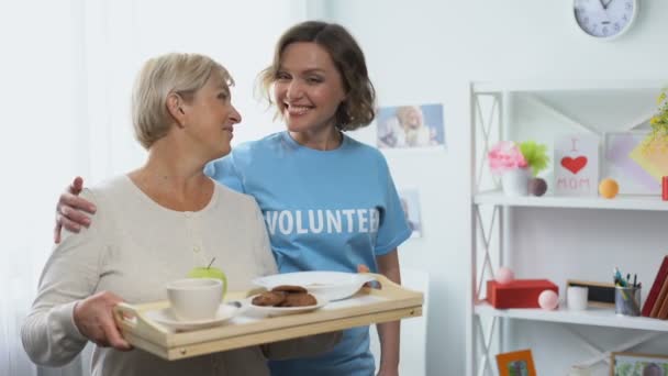 Sozialarbeiterin Umarmt Rentnerin Mit Tablett Mit Essen Freiwilliger Besuch — Stockvideo
