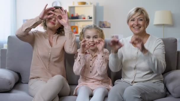 Kind mit Mutter und Oma macht lustige Gesichter, gestikuliert mit den Händen, macht Spaß — Stockvideo