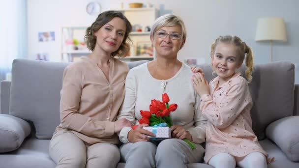 Mor Och Dotter Kramar Mormor Med Tulpaner Och Närvarande Hand — Stockvideo