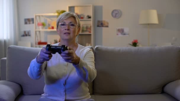 Happy mature lady pressing console buttons playing video game sitting home sofa — Stock Video