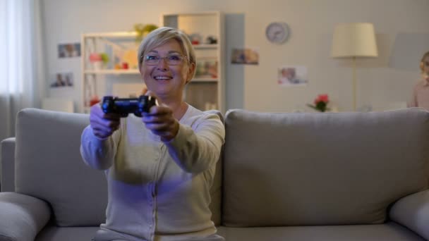 Здивована онука, дивлячись на бабусю, що грає у відеоігри вночі, залежність — стокове відео