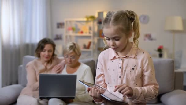 Enkelkind spielt Tablet-Spiel, Mutter und Großeltern nutzen Laptop, Technologie — Stockvideo