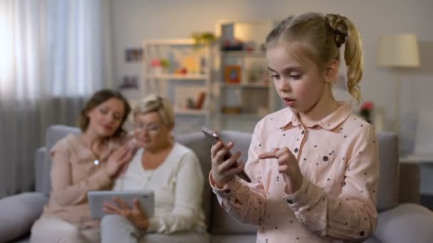 Sonriente niño usando la aplicación para teléfonos inteligentes, abuela y la tableta de desplazamiento madre — Vídeos de Stock