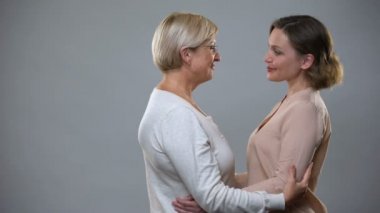 Genç kadın sarılma yaşlı anne üzerinde gri arka plan, Aile bağlantısı, aşk