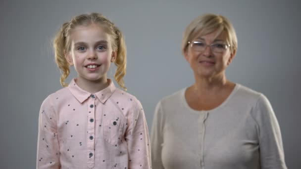 Sevimli Küçük Kız Kameraya Gülümseyen Kıdemli Bayan Arkasında Duran Destek — Stok video