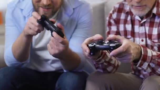 Adult men playing video games using game joysticks, father and son having fun — 图库视频影像