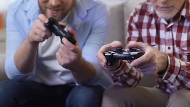 Adult men playing video games using game joysticks, father and son having fun — Stock Video