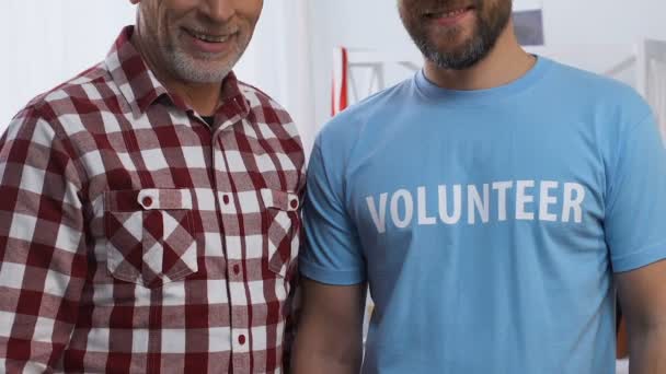 Hombres sonrientes mostrando pulgares hacia arriba, voluntarios ayudando al abuelo jubilado, primer plano — Vídeos de Stock