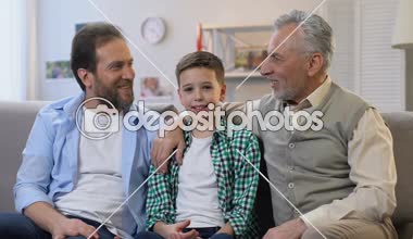Evde kanepede oturan, kamera bakarak mutlu baba ve büyükbaba, çocuk sarılmak