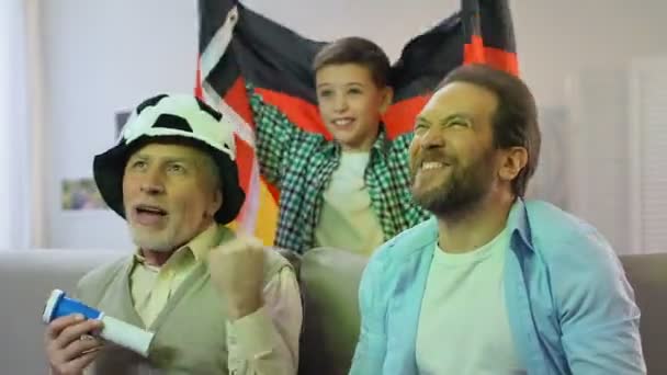 Chłopiec macha flagą Niemiec, Rodzina ogląda mecz reprezentacji piłki nożnej w domu — Wideo stockowe