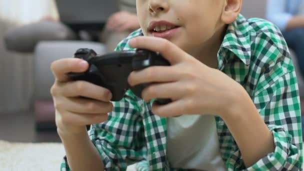 男孩在家玩电子游戏, 家庭在后台使用小工具, 上瘾 — 图库视频影像