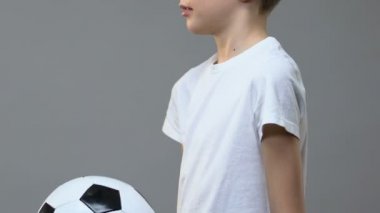 Sevimli çocuk gri arka plan, spor eğlence karşı futbol topu ile oynuyor