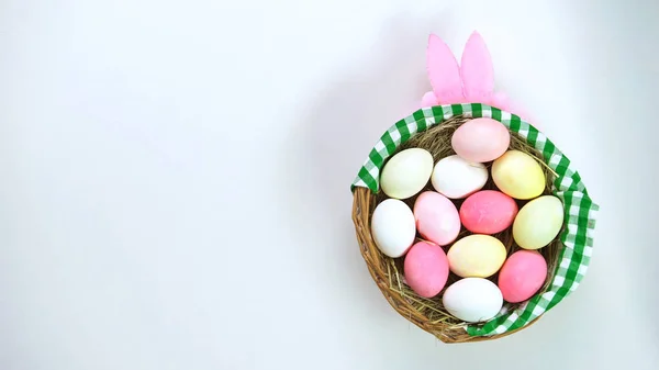 Цветные Пасхальные Яйца Корзине Стоя Столе Повязка Розовыми Кроличьими Ушами — стоковое фото